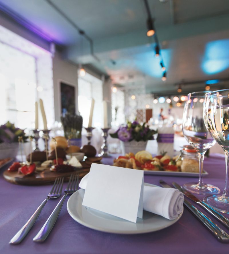 Dining table setting at Provence style, with candles, lavender, vintage crockery and cutlery, closeup.